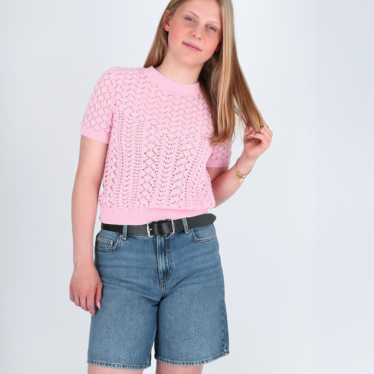 Eine Frau trägt lässige Denim-Shorts und ein rosa Oberteil