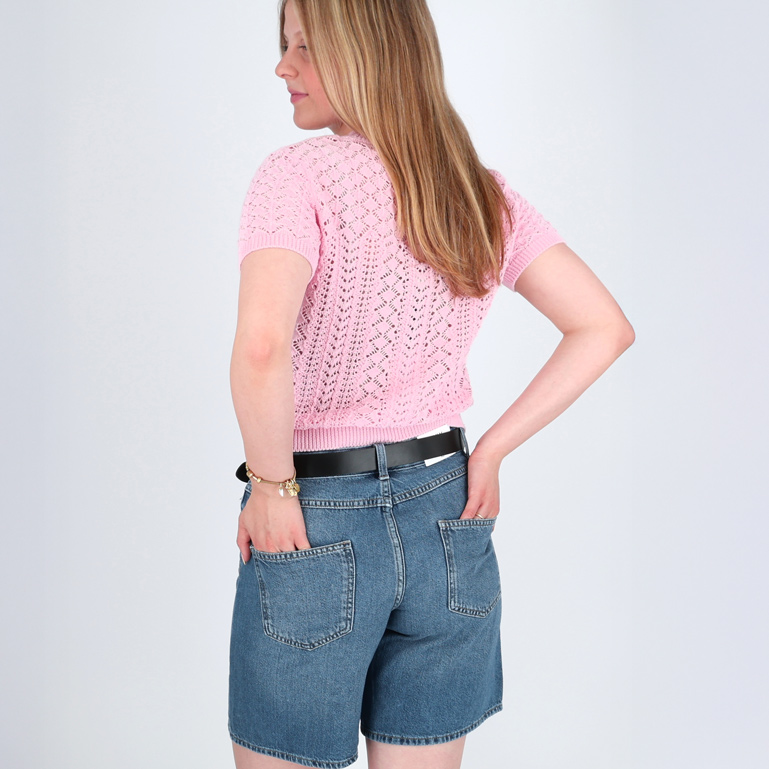 Eine Frau trägt lässige Denim-Shorts und ein rosa Oberteil