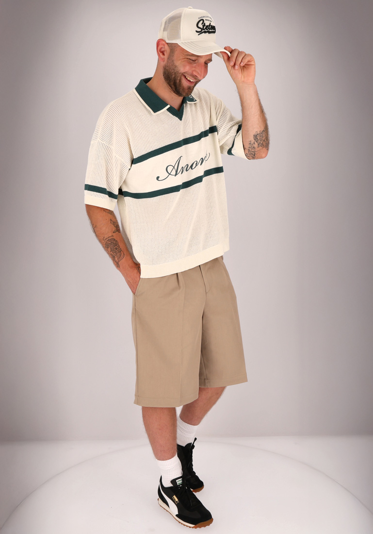 Ein Mann mit Capi, Strickshirt und Shorts.