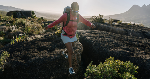 Frau läuft im Wanderoutfit über Felsen