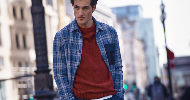 Mann mit karriertem Hemd und rotem Pullover