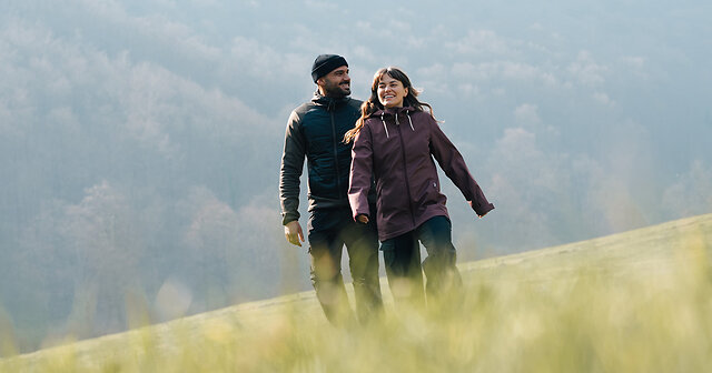 Mann und Frau wandern über ein Feld