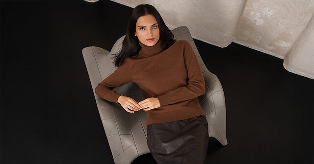 Frau liegt auf einem Stuhl in einem braunem Pullover und Rock