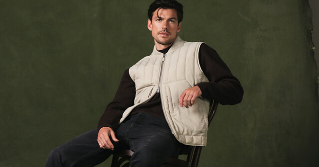 Mann mit heller Weste und dunklem Pullover