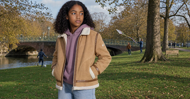 Mädchen mit brauner Jacke mit Schafsfell und lilanem Hoodie