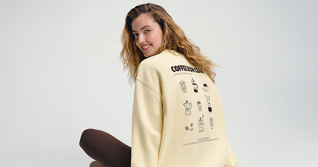 Frau sitzt auf dem Boden im gelben Pullover und brauner Leggings.