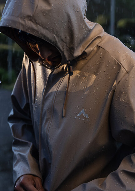 Person mit verdecktem Gesicht in einer beigen Regenjacke