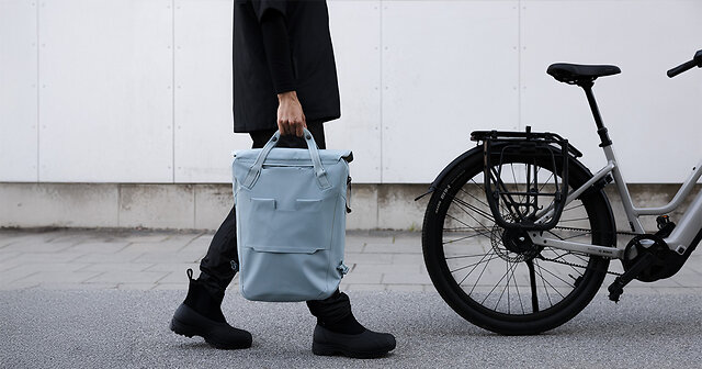 Mann läuft mit blauem Rucksack zu einem Fahrrad