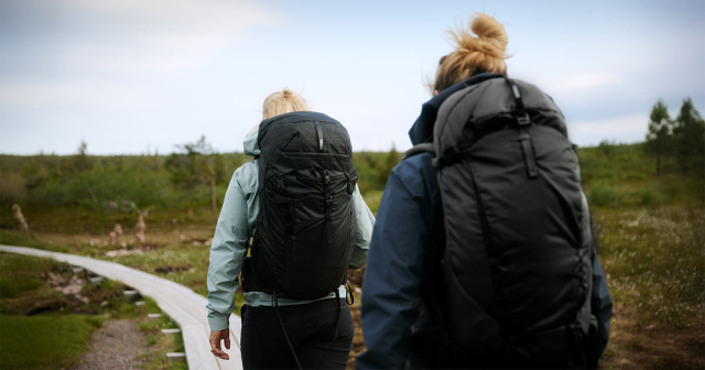 Zwei Frauen von hinten zu sehen mit Wanderrucksack beim Wandern